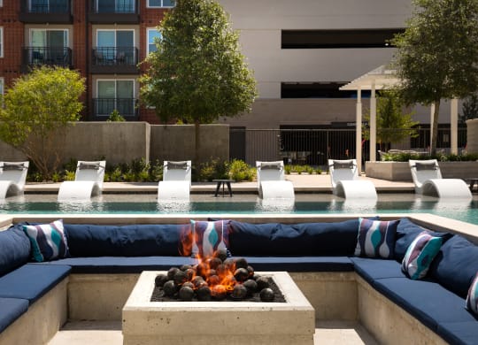 a swimming pool with blue lounge chairs and a fire pit