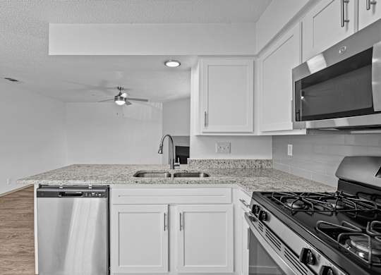 A kitchen with a stove, sink, and microwave.