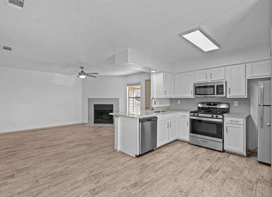 A spacious kitchen with a wood floor and white appliances.