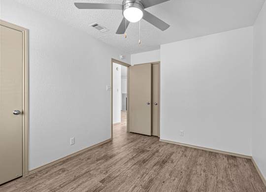 A room with a ceiling fan and wood flooring.