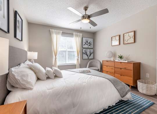 A bedroom with a bed, nightstand, and a ceiling fan.