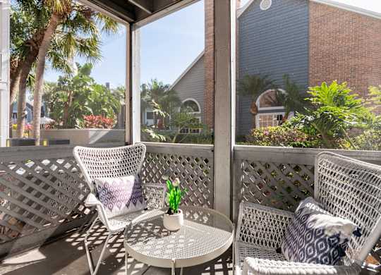 A patio with two chairs and a table with a vase of flowers on it.