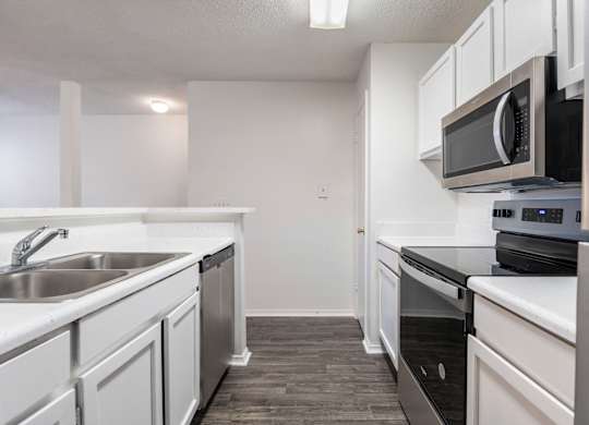 A kitchen with white cabinets and black countertops.