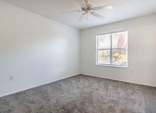 A room with a ceiling fan and a window with blinds.