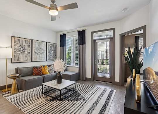 A living room with a grey couch, a coffee table, and a ceiling fan.