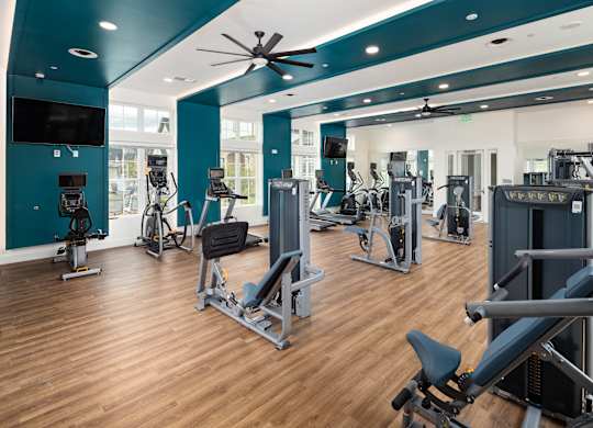 A gym with a variety of equipment including treadmills, weights, and exercise machines.