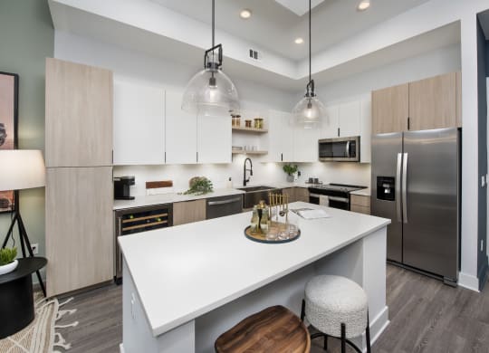 an open kitchen with a large white island and stainless steel appliances