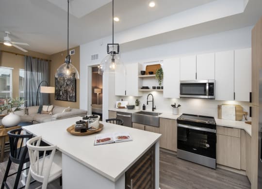 an open kitchen and living room with a large white island and a dining table