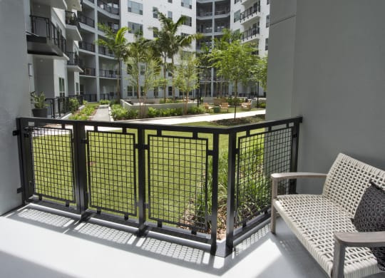 a balcony with a couch and a chair overlooking a courtyard