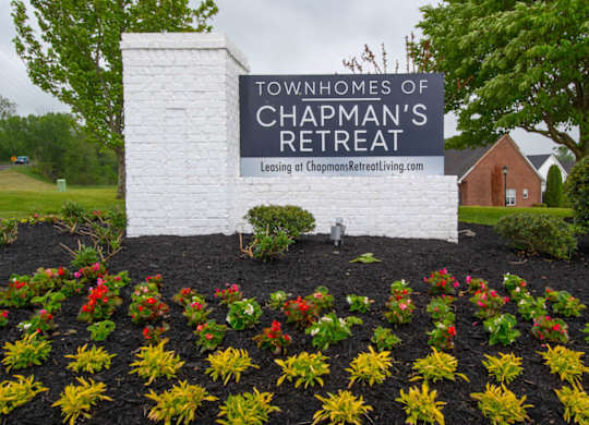 A sign for the Townhomes of Chapman's Retreat is surrounded by flowers.