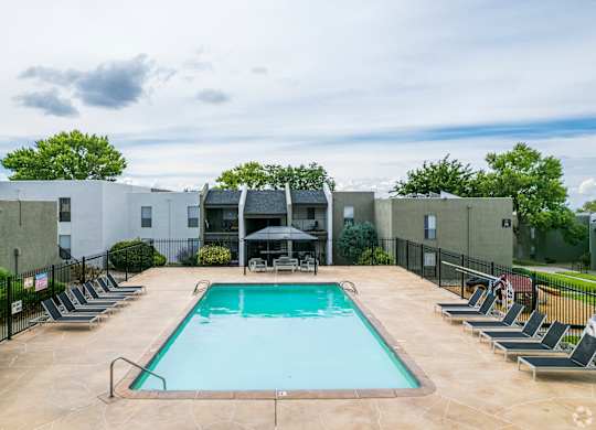 A swimming pool surrounded by lounge chairs and umbrellas.