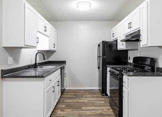 A kitchen with black appliances and white cabinets.