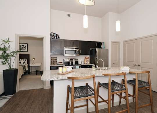 A kitchen with a marble countertop and wooden chairs.