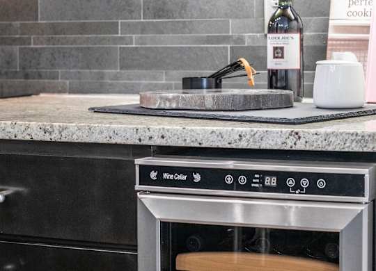 A kitchen with a wine bottle and a sign that says