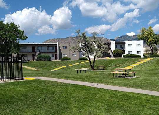 a grassy area with trees and buildings in the background