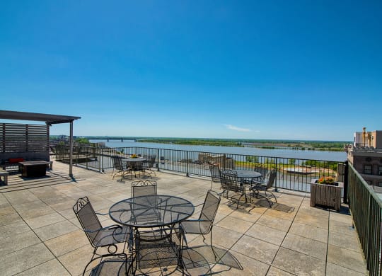 a large patio with tables and chairs overlooks a body of water