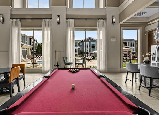 A pool table in a room with a view of the outside.