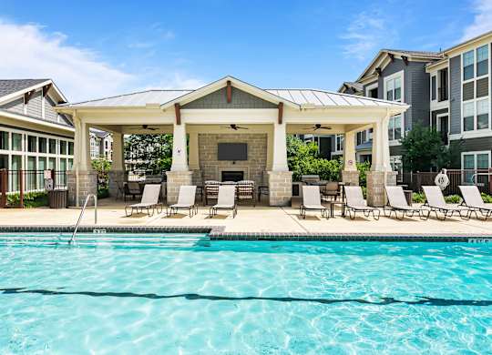 A swimming pool with a pavilion and chairs around it.
