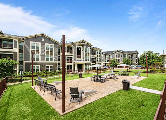 A sunny day at a residential complex with a grassy area and chairs.
