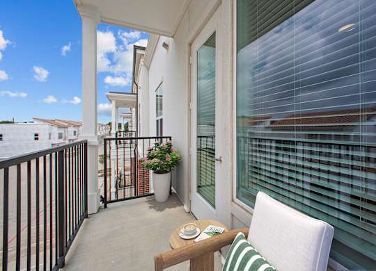 A balcony with a table, chairs and a potted plant.