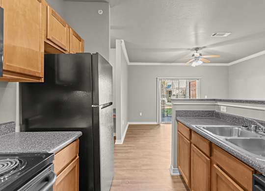 A kitchen with a black refrigerator and wooden cabinets.