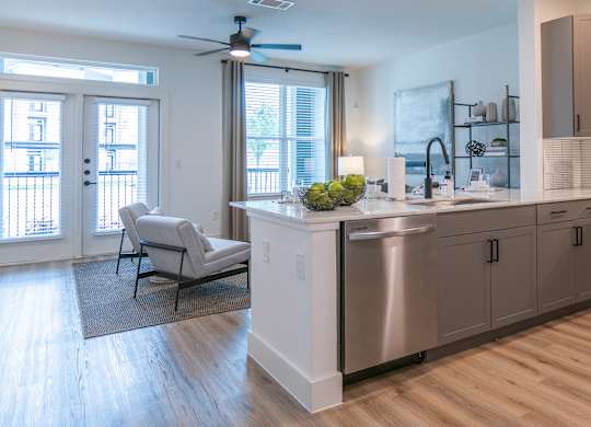 A modern kitchen with a large island and a balcony with a chair.