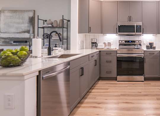 A modern kitchen with stainless steel appliances and wooden floors.