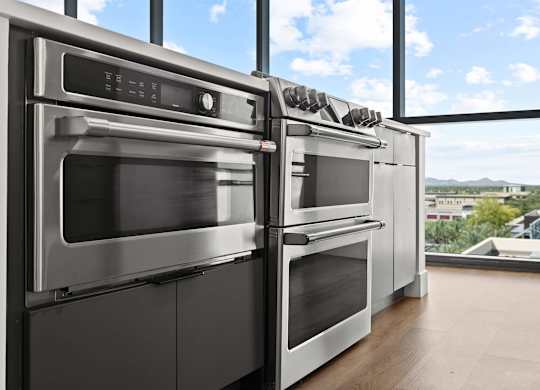 A row of modern stainless steel ovens in a kitchen.
