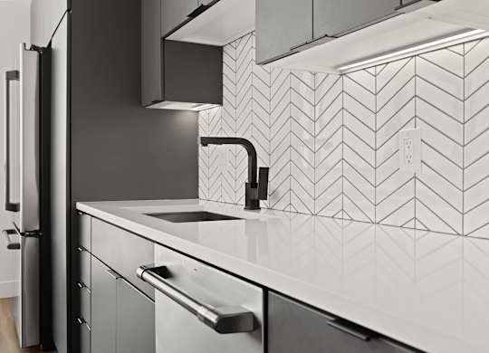 A modern kitchen with a black fridge and a white sink.