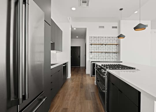 A modern kitchen with a stainless steel refrigerator and black cabinets.