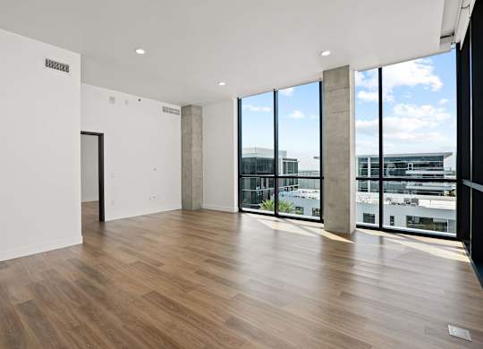 A room with wooden floors and a view of the city through large windows.