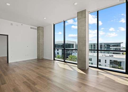 A room with a wooden floor and a view of the city through the windows.