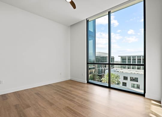 A room with a ceiling fan and a view of the city.