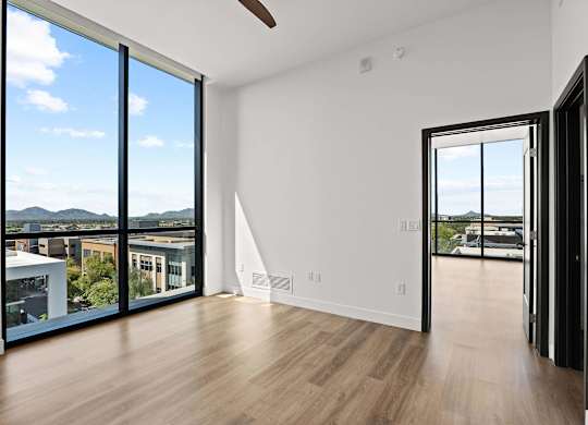 A room with a sliding glass door leading to a balcony with a view of the mountains.