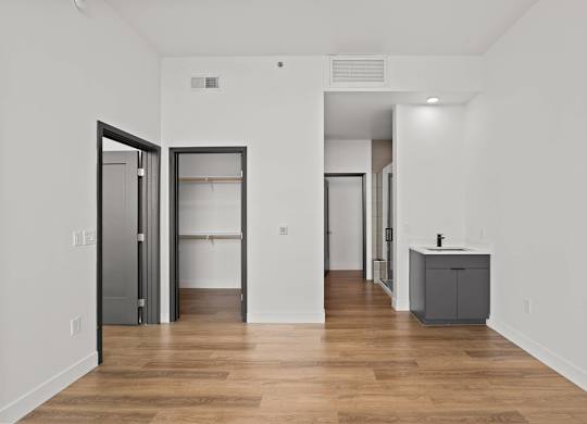 A room with a wooden floor and white walls with a grey cabinet and a wardrobe.
