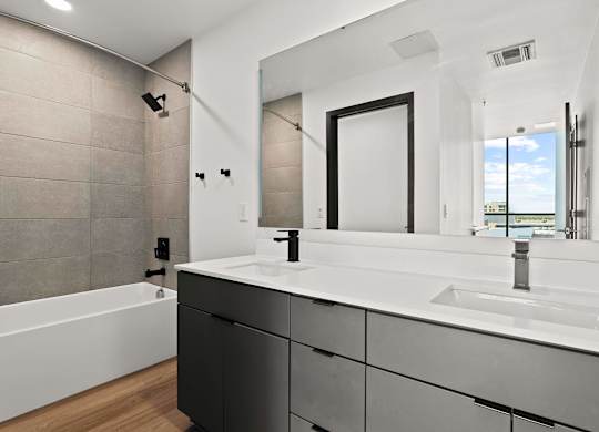 A modern bathroom with a white sink and black cabinets.