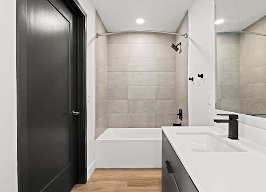 A modern bathroom with a black door and a white bathtub.