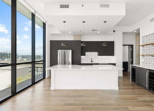 A modern kitchen with a large island and a view of the city.