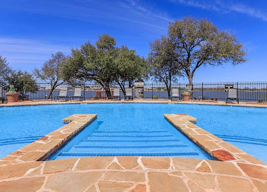 A swimming pool with a stone border and steps leading into the water.
