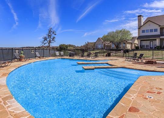 A large outdoor swimming pool surrounded by a stone border.