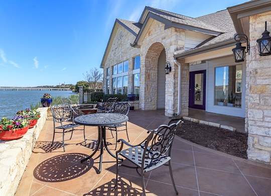 A patio with a table and chairs overlooking a body of water.