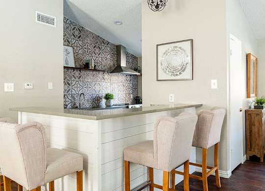 A kitchen with a bar area and chairs.