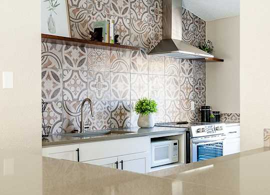 A kitchen with a patterned backsplash and a stove top oven.