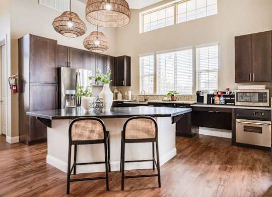 A kitchen with a black refrigerator and wooden floors.