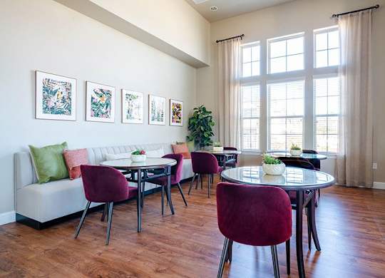 A living room with a white couch, a dining table with chairs, and pictures on the wall.