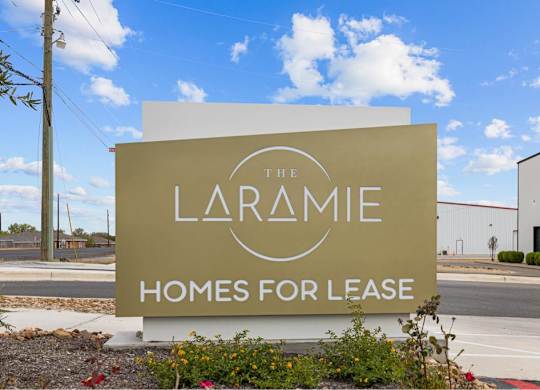 A sign for The Laramie Homes for Lease is displayed in front of a building.