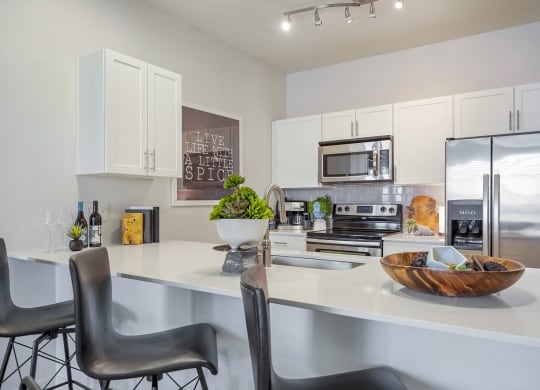 an open kitchen with a large counter with chairs