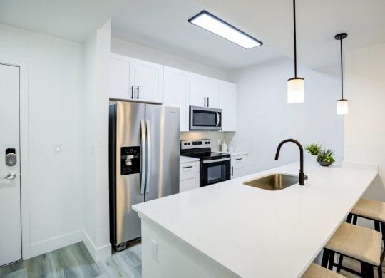 a kitchen with a white counter top and a stainless steel refrigerator