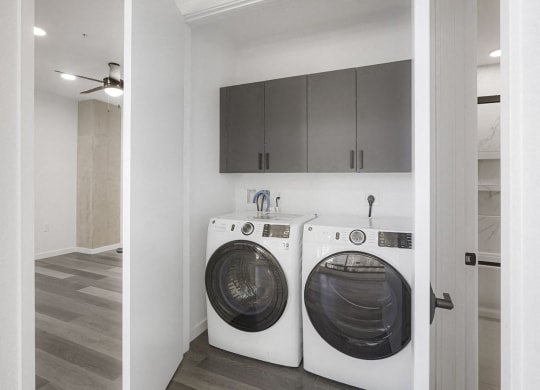 a washer and dryer in a laundry room with white cabinets