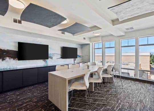 a conference room with a long table and chairs and televisions